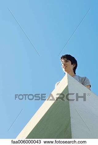 Young man, low angle view with sky in background View Large Photo Image Stock Image - Young man, low angle view with sky in background. Fotosearch