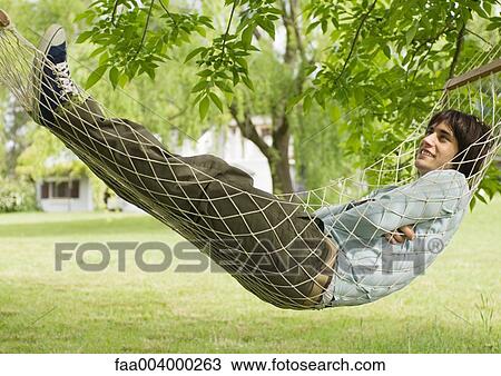 Young man lying in hammock View Large Photo Image Stock Image - Young man lying in hammock. Fotosearch