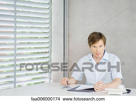 Young man sitting at desk View Large Photo Image Picture - Young man sitting at desk. Fotosearch