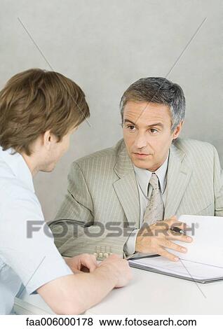 Stock Photo - Young man with mature businessman, discussing document. Fotosearch