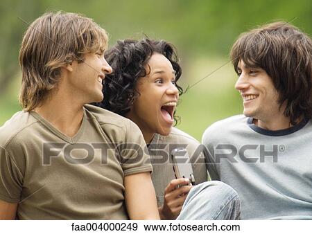 Young woman holding cell phone and screaming, between two friends View Large Photo Image Stock Photo - Young woman holding cell phone and screaming, between two friends. Fotosearch