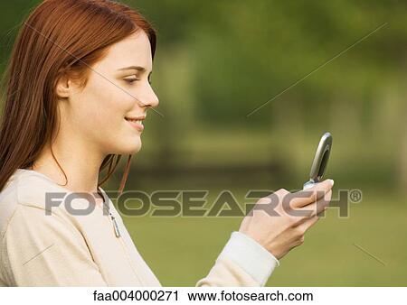 Young woman looking at cell phone, side view View Large Photo Image Stock Image - Young woman looking at cell phone, side view. Fotosearch