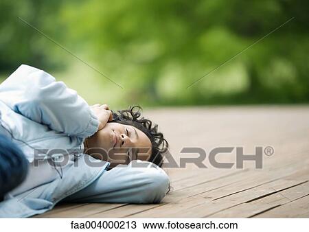Young woman lying down outdoors View Large Photo Image Stock Image - Young woman lying down outdoors. Fotosearch