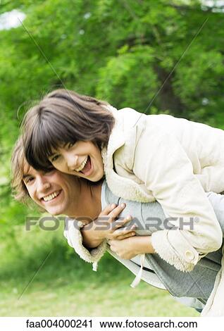 Young woman on man's back, smiling View Large Photo Image Stock Image - Young woman on man's back, smiling. Fotosearch