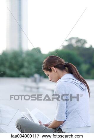 Young woman reading outdoors on college campus View Large Photo Image Stock Photo - Young woman reading outdoors on college campus. Fotosearch