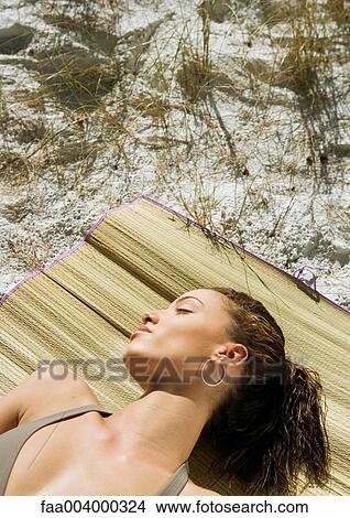 Picture - Young woman sleeping on beach mat. Fotosearch