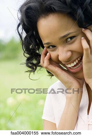 Young woman smiling with hands on side of face View Large Photo Image Stock Photography - Young woman smiling with hands on side of face. Fotosearch