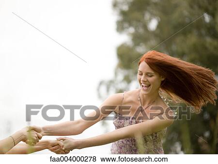 Young woman spinning around with friend outdoors View Large Photo Image Stock Photo - Young woman spinning around with friend outdoors. Fotosearch