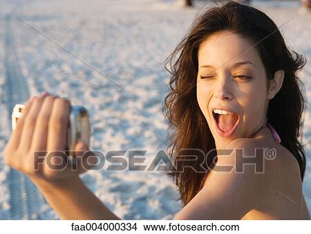 Young woman taking photo of self on beach View Large Photo Image Picture - Young woman taking photo of self on beach. Fotosearch