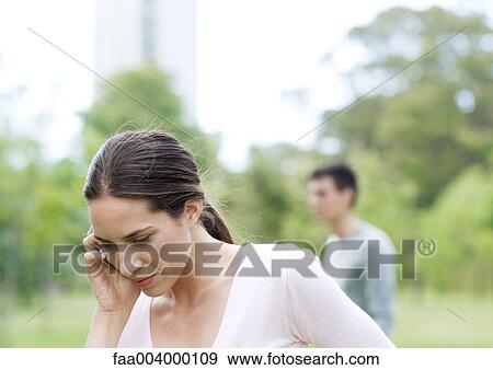 Stock Photo - Young woman using cell phone in city park. Fotosearch