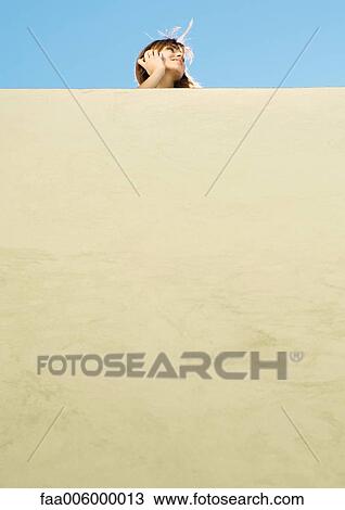 Stock Image - Young woman using cell phone, low angle view. Fotosearch