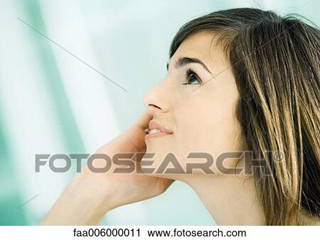 Stock Image - Young woman using cell phone, side view. Fotosearch