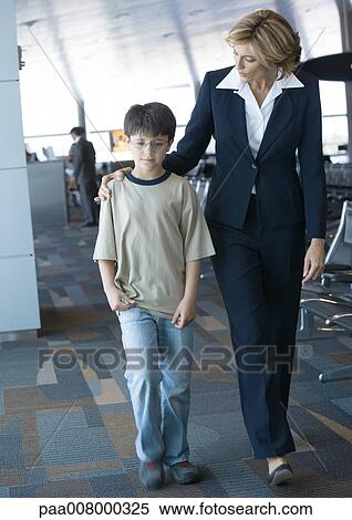 Airline attendant walking with boy in airport View Large Photo Image Stock Photography - Airline attendant walking with boy in airport. Fotosearch