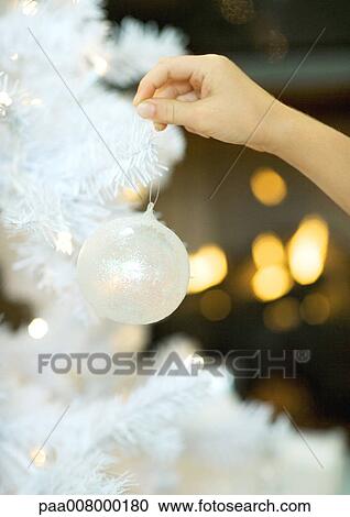 Stock Image - Child hanging christmas ornament on tree. Fotosearch