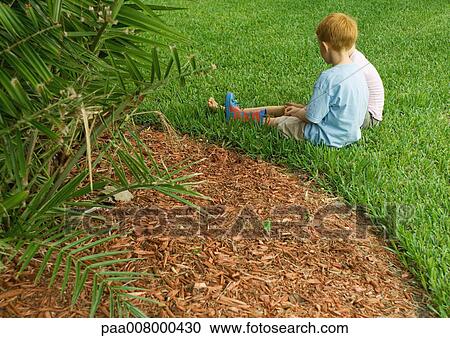 Stock Image - Children sitting in grass. Fotosearch