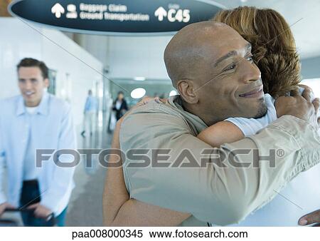 Stock Photography - Couple hugging in airport. Fotosearch