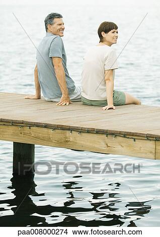 Couple sitting on edge of dock View Large Photo Image Picture - Couple sitting on edge of dock. Fotosearch