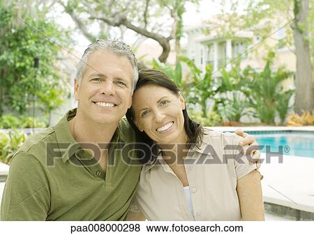 Stock Photo - Couple standing in front of pool, smiling. Fotosearch