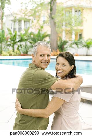 Couple standing in front of pool, smiling View Large Photo Image Stock Photo - Couple standing in front of pool, smiling. Fotosearch