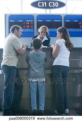 Family standing at airline check-in counter View Large Photo Image Stock Photo - Family standing at airline check-in counter. Fotosearch