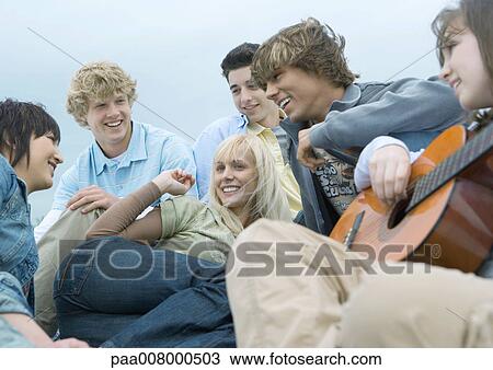 Friends hanging out together, one playing guitar View Large Photo Image Stock Image - Friends hanging out together, one playing guitar. Fotosearch