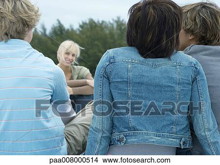 Picture - Friends hanging out together outdoors, rear view. Fotosearch