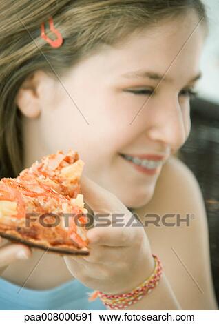 Stock Image - Girl holding slice of pizza. Fotosearch