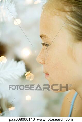 Stock Image - Girl looking at christmas tree, close-up. Fotosearch