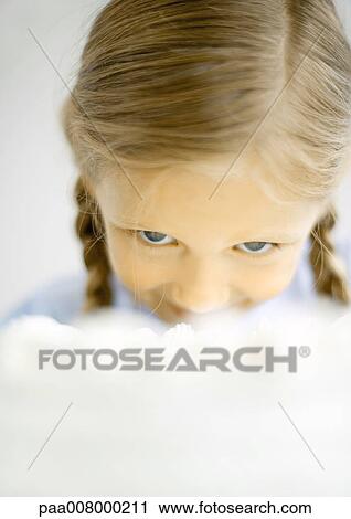 Stock Image - Girl lowering head to eat cake. Fotosearch