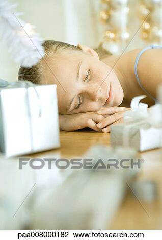 Stock Image - Girl lying on floor next to Christmas tree. Fotosearch