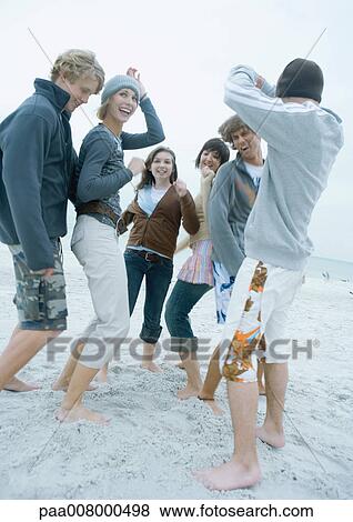 Stock Photo - Group of young adult friends dancing on beach. Fotosearch