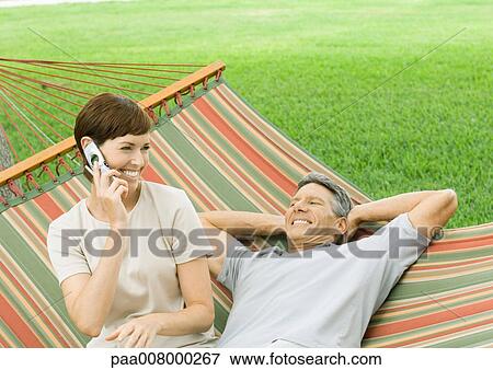 Mature couple lounging in hammock, woman using cell phone View Large Photo Image Stock Photo - Mature couple lounging in hammock, woman using cell phone. Fotosearch