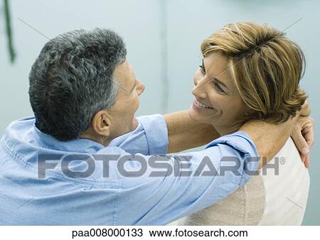 Mature couple smiling at each other, man with arms around woman's neck View Large Photo Image Stock Image - Mature couple smiling at each other, man with arms around woman's neck. Fotosearch