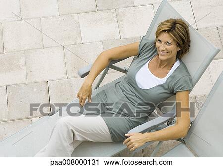 Stock Image - Mature woman in lounge chair, high angle view. Fotosearch