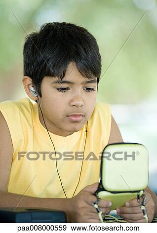 Preteen boy wearing earphones and holding case View Large Photo Image Stock Photo - Preteen boy wearing earphones and holding case. Fotosearch