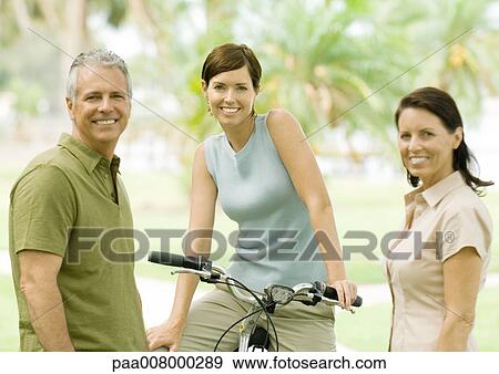 Smiling adults, one on bike View Large Photo Image Stock Photo - Smiling adults, one on bike. Fotosearch
