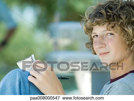 Teenage boy sitting with pen and notebook, side view View Large Photo Image Stock Photo - Teenage boy sitting with pen and notebook, side view. Fotosearch