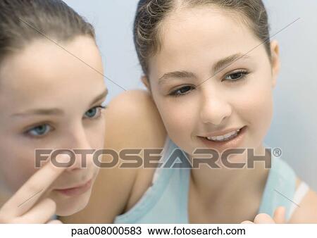 Teenage girl touching nose while friend watches View Large Photo Image Stock Image - Teenage girl touching nose while friend watches. Fotosearch