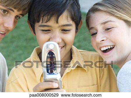 Three preteen kids looking at cell phone View Large Photo Image Stock Photo - Three preteen kids looking at cell phone. Fotosearch