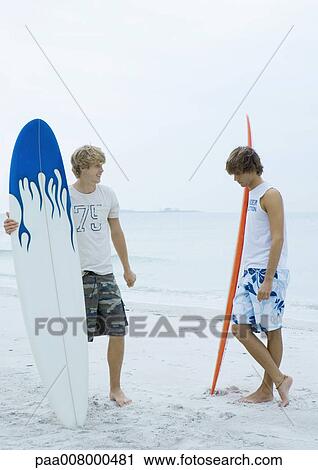 Two surfers standing on beach View Large Photo Image Stock Image - Two surfers standing on beach. Fotosearch