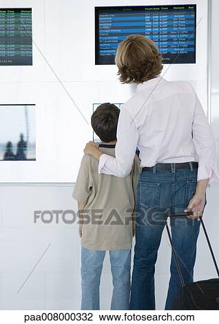 Woman and boy looking at arrival and departure boards in airport, rear view View Large Photo Image Stock Image - Woman and boy looking at arrival and departure boards in airport, rear view. Fotosearch