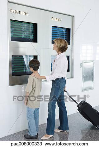 Woman and boy looking at departure board in airport View Large Photo Image Stock Image - Woman and boy looking at departure board in airport. Fotosearch