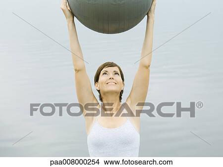 Woman exercising with fitness ball, next to lake View Large Photo Image Picture - Woman exercising with fitness ball, next to lake. Fotosearch