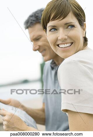Woman looking away, smiling, as man reads newspaper View Large Photo Image Stock Image - Woman looking away, smiling, as man reads newspaper. Fotosearch