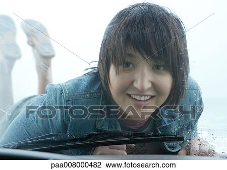 Woman lying on hood of car, looking through windshield View Large Photo Image Stock Image - Woman lying on hood of car, looking through windshield. Fotosearch