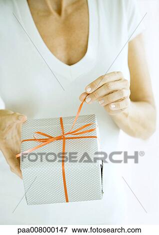 Stock Photo - Woman pulling ribbon on present. Fotosearch