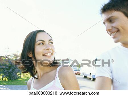 Stock Photo - Young couple going for walk in residential neighborhood. Fotosearch