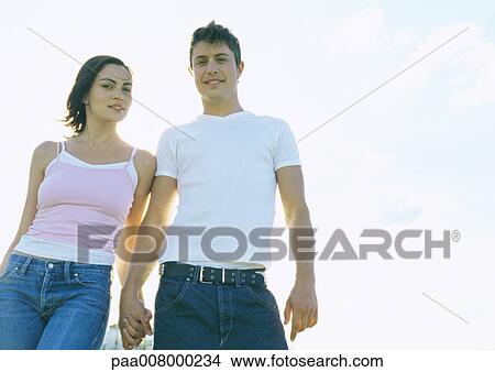 Young couple holding hands, low angle view View Large Photo Image Picture - Young couple holding hands, low angle view. Fotosearch