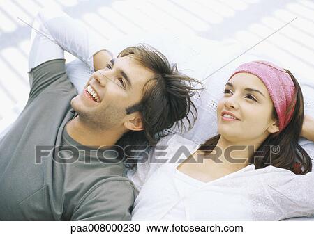 Stock Image - Young couple lying on backs, relaxing. Fotosearch