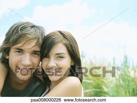 Young couple smiling, outdoors View Large Photo Image Stock Photograph - Young couple smiling, outdoors. Fotosearch